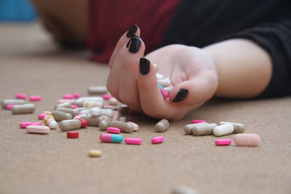 young woman lying on floor after overdosing on oxycodone, percocet and xanax